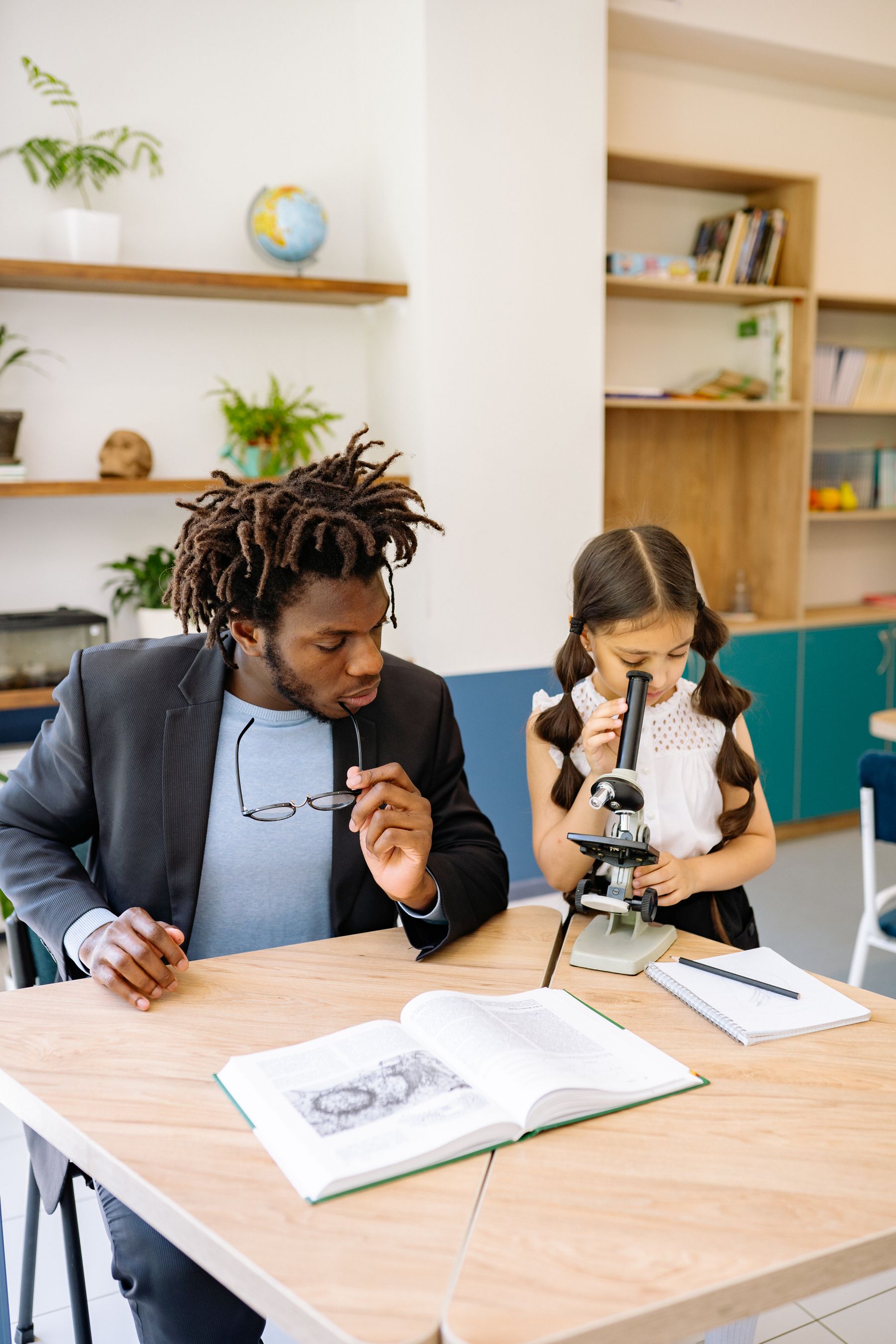 A facilitator working with a young girl at a microscope