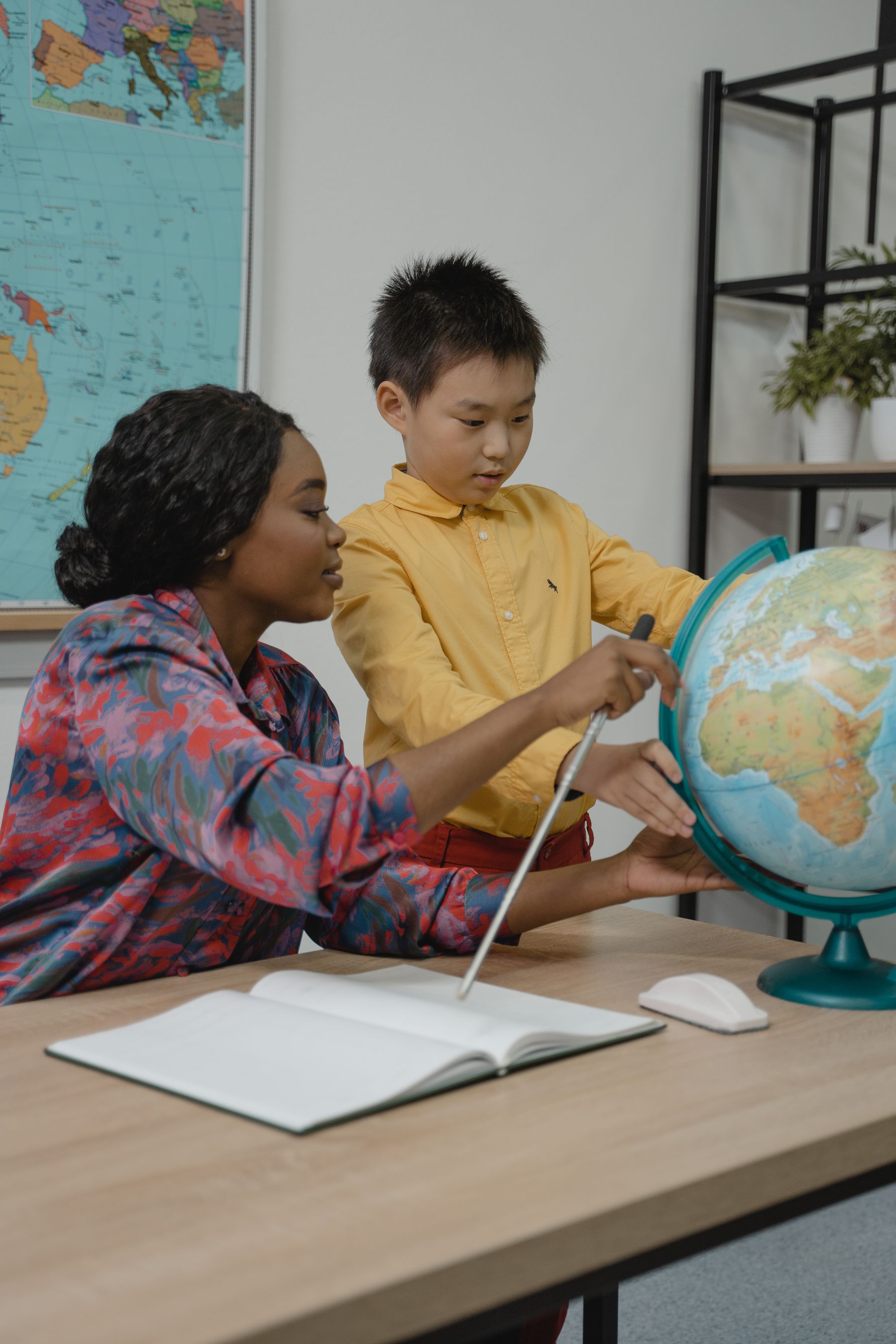 A facilitator and a young boy exploring a globe together